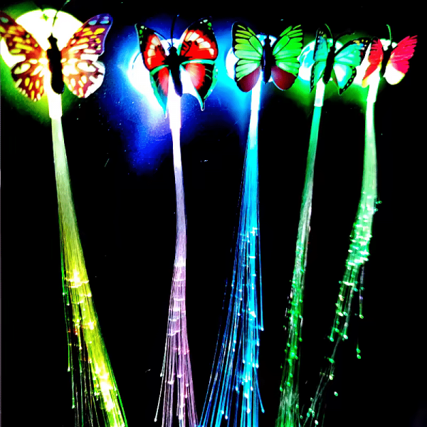 Enchanting LED Hair Extensions feature colorful fibers that glow in blue, green, and red against a dark background, creating a bright and magical effect akin to fiber optic butterflies.
