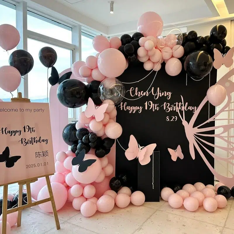 A stylish birthday setup features pink and black balloons around a black backdrop with butterflies and Chen Ying Happy 19th Birthday 8.29 written on it. A welcome sign reads Welcome to my party with the date 2025.1.01 displayed.